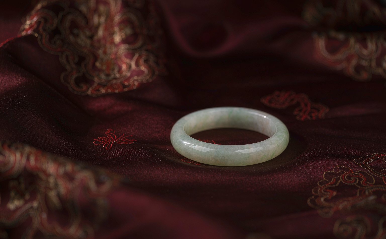 婚嫁场景氛围图:红色绸缎上的翡翠手镯